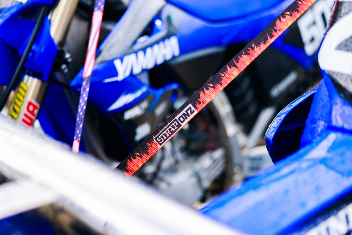Strap Onz ratchet strap in the Flames design holding down a blue dirt bike